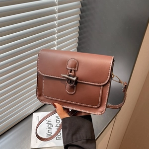 Detail of vintage brown leather bag with white stitching and toggle hook metal closure