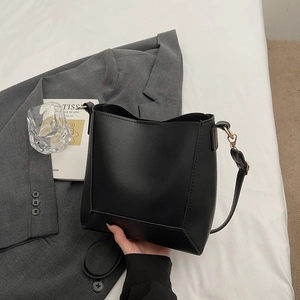 Detail of matte black leather bucket bag with gold buckle and adjustable strap
