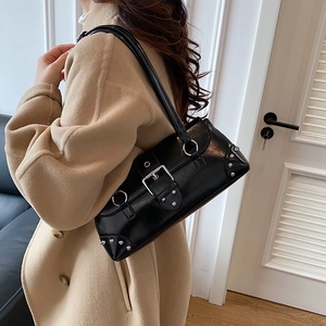 Schwarze Lackleder-Achseltasche mit Silberschnalle und Nieten auf beigem Mantel