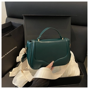 Detail of dark green leather handbag in luxury gift box with white wide shoulder strap