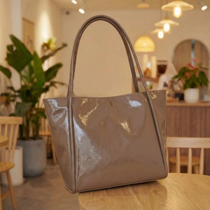 Minimalist glossy beige tote bag on a wooden table in a warm coffee shop setting