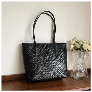 Detailed view of black woven texture on a large capacity tote bag with leather straps