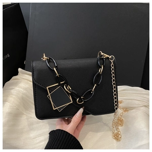 Detail of black leather flap bag featuring bold resin chain and gold metal shoulder strap