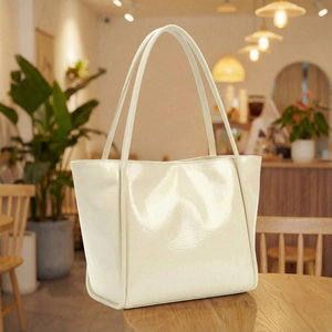 Chic cream patent leather tote bag for women with long shoulder straps in cafe setting