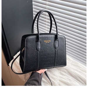 Detail of black crocodile texture Boston bag with gold lettering on lace background