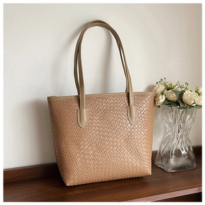 Detail of woven texture on camel leather tote bag with slim shoulder straps