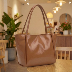 Minimalist caramel brown patent leather tote bag shown on a table in a cafe