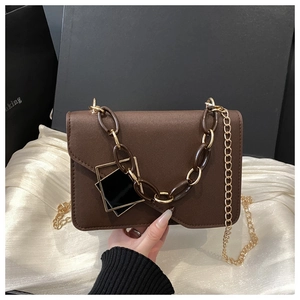 Detail of dark brown leather crossbody bag with dual-tone chain and geometric hardware buckle
