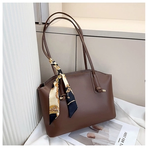Detail of dark brown tote bag featuring a decorative printed silk scarf on the handle