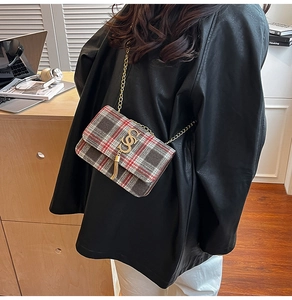 Détail du sac bandoulière en tweed à carreaux avec chaîne dorée et franges sur cuir noir