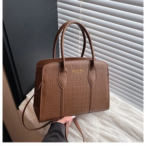 Detailed macro view of brown crocodile texture and gold lettering on a stylish Boston bag