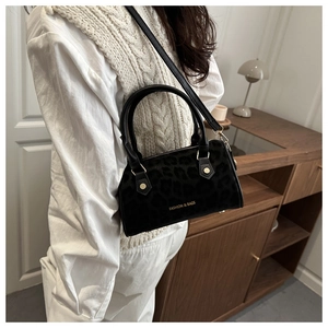 Détail du sac Boston noir à motif léopard avec rivets dorés et bandoulière en cuir souple