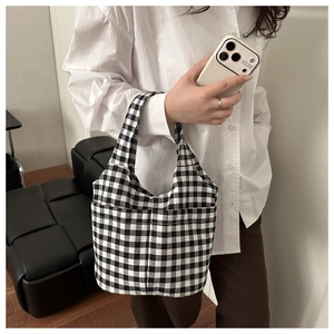 Close-up of black and white gingham canvas tote bag featuring an outer front pocket