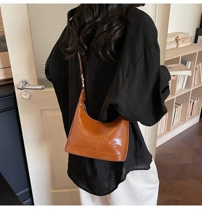 Brown half-moon handbag with embossed lettering on model back in a cozy room