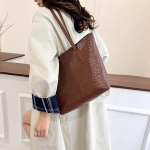 Brown large capacity tote bag with woven texture shown on model in modern interior