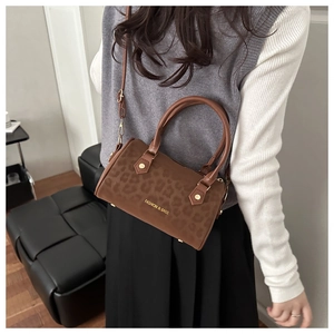 Détail du sac cylindre léopard avec poignées en cuir et lettrage doré élégant