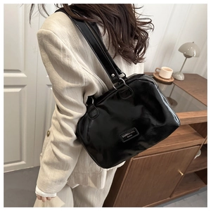 Vue détaillée du sac Boston noir brillant avec boucle métallique et bandoulière