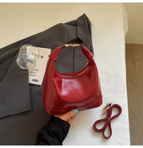 Close-up of red patent leather Hobo bag with embossed logo and gold metal zipper detail