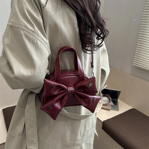 Elegante borsa a mano rosso scuro con fiocco e stelle argentate, indossata con trench