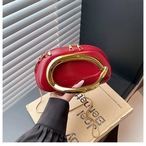 Details einer roten Lackledertasche mit markantem goldenem Rundgriff und Doppelreißverschluss