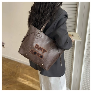 Detail view of vintage dark brown faux leather tote with textured surface and embroidery