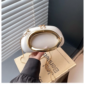 Detail der weißen glänzenden Ledertasche mit ihrem markanten ovalen goldenen Metallgriff