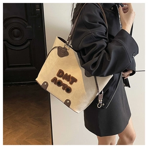 Detailed side view of the beige tote bag showing reinforced leather corners and trapezium shape