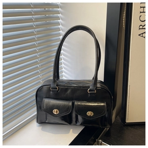 Close-up of retro black shiny leather pillow bag with gold twist-lock front pockets
