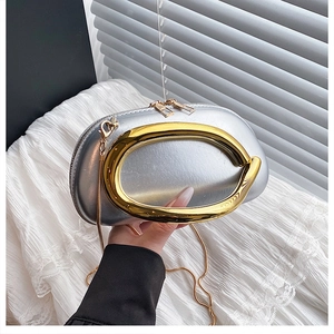 Nahaufnahme der halbkreisförmigen silbernen Clutch mit großem goldenem Metallgriff