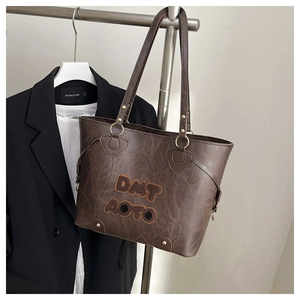 Detail of dark brown leather tote bag with vintage texture and golden ring hardware