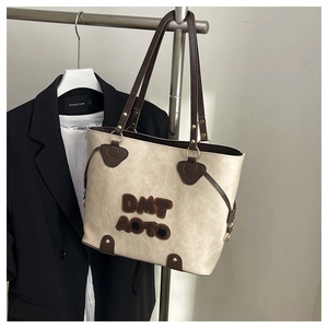 Close-up of the beige tote bag with plush letters and brown faux leather straps