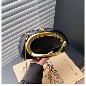 Detail der glänzenden schwarzen Handtasche mit großem Goldgriff und feiner Metallkette