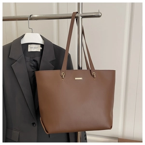 Detail of dark brown leather tote bag with gold hardware shown on a stylish outfit
