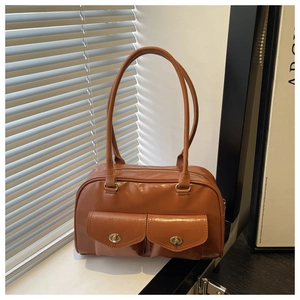 Detail of vintage brown tote bag featuring dual front pockets and metal swivel buckles