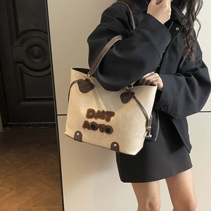 Retro cream tote bag with brown leather trim and fuzzy 3D lettering on a model