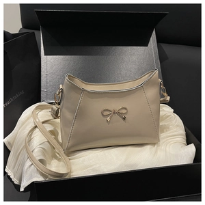Dettaglio della borsa crema con fiocco dorato in elegante confezione regalo nera