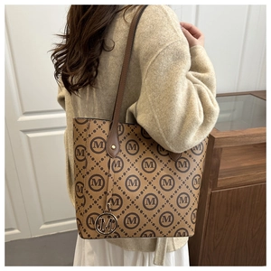 Sac fourre-tout marron avec motif monogramme M et breloque dorée sur mannequin femme