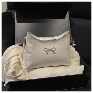 Dettaglio di borsa beige con fiocco in una confezione regalo nera con fodera in seta