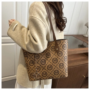 Détail du sac cabas marron avec motif monogramme M et pendentif en métal doré