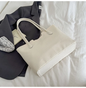 Detail of cream white tote bag with scalloped edges and textured embossed synthetic leather