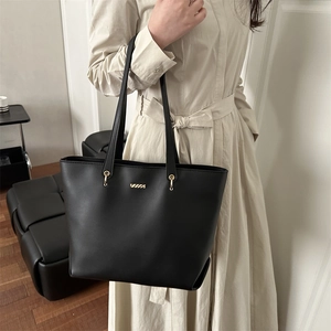 Minimalist black leather tote bag with gold logo shown on model for daily commuting