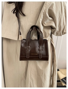 Detailed view of the dark brown leather shoulder bag with gold FASHION & BAGS lettering
