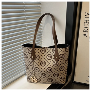 Détail du sac cabas vintage avec monogramme, anses en cuir et pendentif doré en M