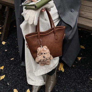Bolso cubo de cuero sintético marrón con colgante de perro en un ambiente otoñal elegante