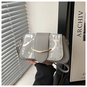 Détail d'un sac à main gris en cuir avec imprimé argenté et fermoir croissant doré chic