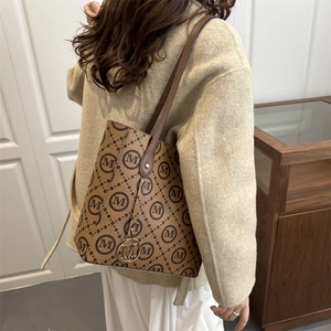 Sac fourre-tout marron avec monogramme M vintage et pendentif doré porté à l'épaule