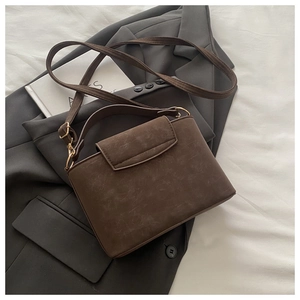 Detail of dark brown vintage faux leather handbag with matte texture and top handle
