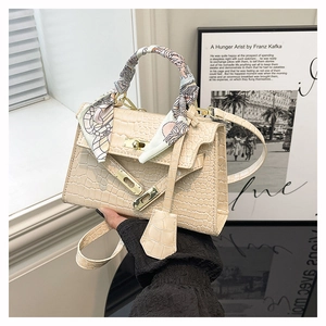 Detailed macro view of cream crocodile embossed leather texture and gold buckle on a handbag