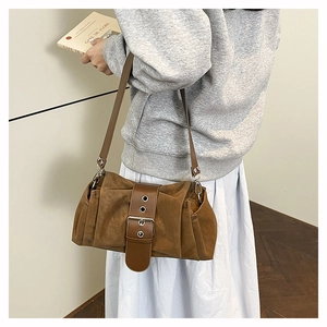 Gros plan du sac bandoulière en daim marron avec plis texturés et boucle métallique