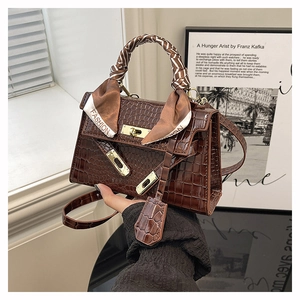 Detailed shot of dark brown crocodile pattern handbag with a silk scarf wrapped on the handle